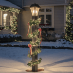 A photo of a tall, lighted Christmas lamppost decorated with ribbons, standing in the front garden.