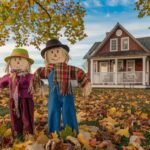 a picturesque fall scene with two wooden scarecrows in the yard