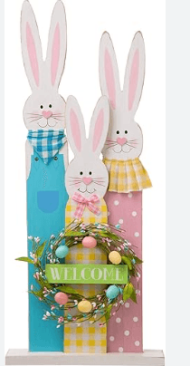 Wooden Easter bunny decoration featuring three bunnies in pastel colors, each with different outfits and accessories, standing beside a floral wreath with a "Welcome" sign, perfect for spring and holiday decor.