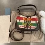 Gucci Music handbag displayed with dust bag, care card, and packaging, showcasing vibrant design and luxury branding in a stylish arrangement.