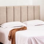 Modern bedroom featuring a stylish upholstered headboard, white bedding, and a cozy throw, enhancing the aesthetic appeal and comfort of the space.