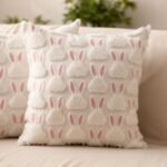 Two decorative pillows with a bunny pattern, featuring soft white fabric and pink accents, placed on a light-colored sofa in a cozy living space.