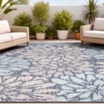 Stylish outdoor seating area featuring a floral patterned rug, modern wicker furniture, and lush greenery for a relaxing atmosphere.