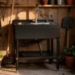 Modern gardening sink in a rustic shed, surrounded by potted plants and gardening tools, ideal for outdoor cleaning and potting tasks.