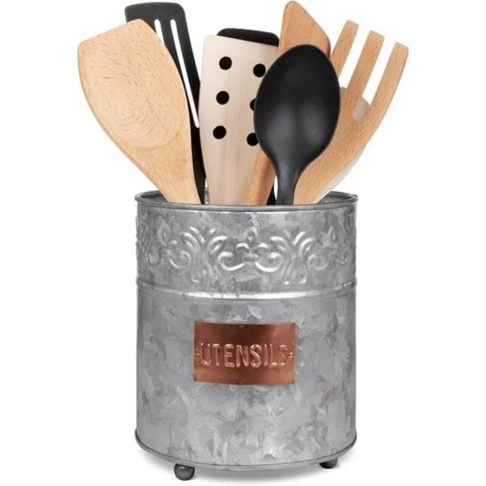Metal utensil holder filled with wooden and plastic kitchen tools, featuring a decorative design and a copper label for organization and style.