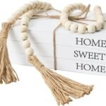 Decorative wooden bead garland with tassels resting on stacked books, perfect for home decor and interior styling.