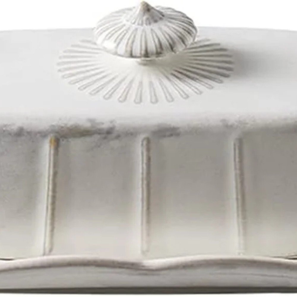 Elegant white ceramic butter dish with a decorative lid, featuring ribbed detailing and a classic design, perfect for kitchen decor and serving.