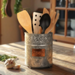 Metal container filled with wooden cooking utensils, including spatulas and spoons, on a rustic kitchen table with garlic and herbs in natural light.