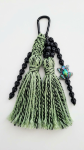 Handcrafted green tassel keychain featuring black skull beads and a colorful frog charm, perfect for adding a unique touch to your accessories.