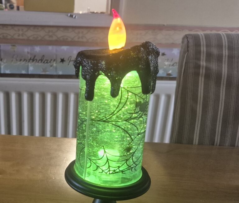 Glowing green Halloween candle with spiderweb design, perfect for the best Halloween decor to transform your space.
